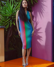 Charger l'image dans la galerie, Woman in a colorful dress standing against a pink wall with greenery