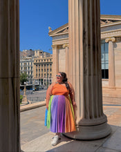 Charger l'image dans la galerie, Woman in colorful dress standing between ancient columns with a cityscape in the background