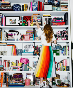Jamie Meares wearing the Chroma skirt with a white top, reaching up at a bookshelf